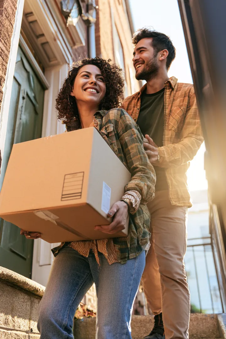 Couple carrying a labeled box on the kind of moving day a 1500 dollar loan often funds