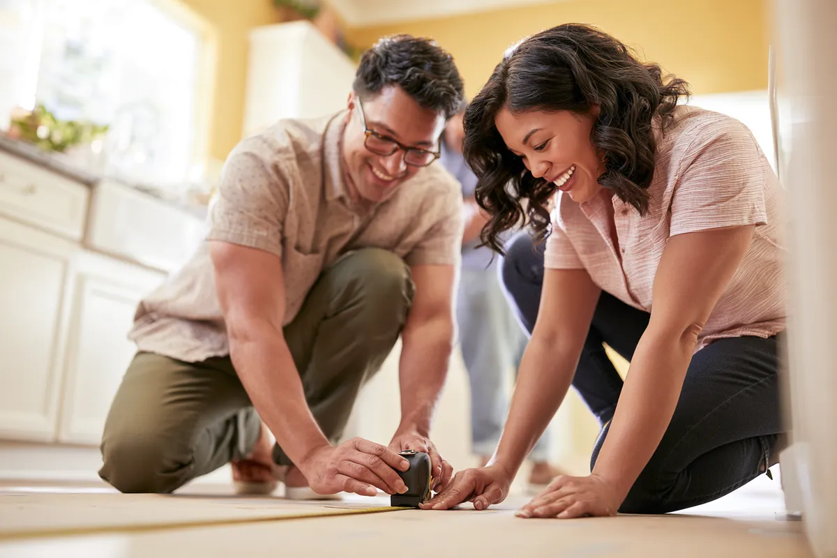 Couple measuring their kitchen for the appliance replacement a $2,000 loan will cover